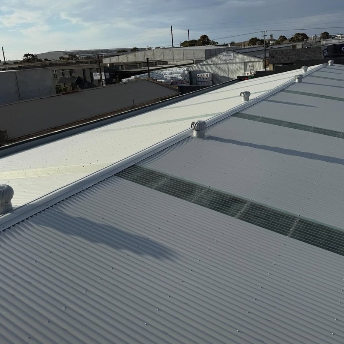 The same roof with new pale metal sheets, clear sheets and whirlybirds